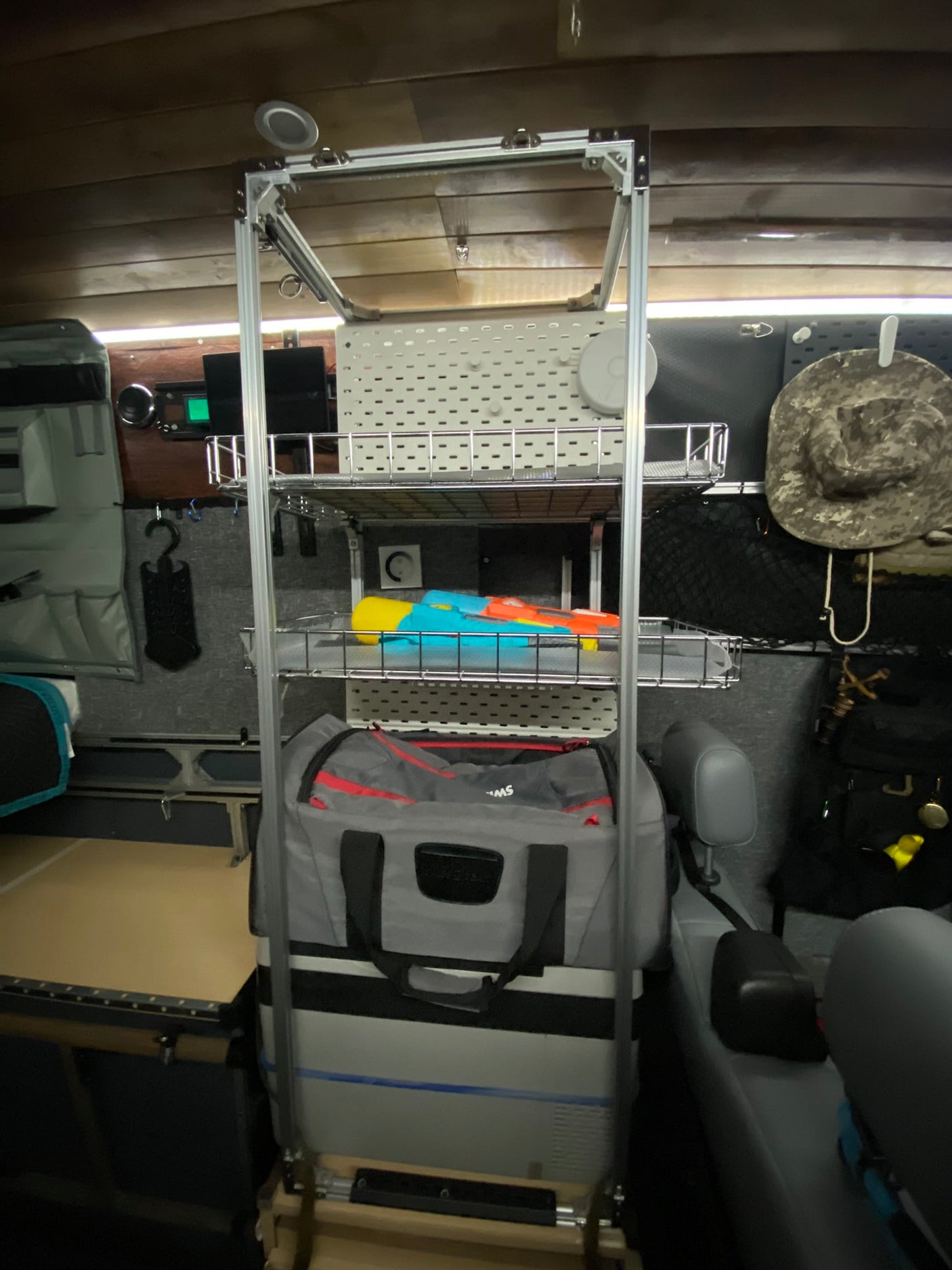 RV rental interior with a tall aluminum shelving unit. Provides organized campervan storage for cooler, bags, and toys, ready for adventure.