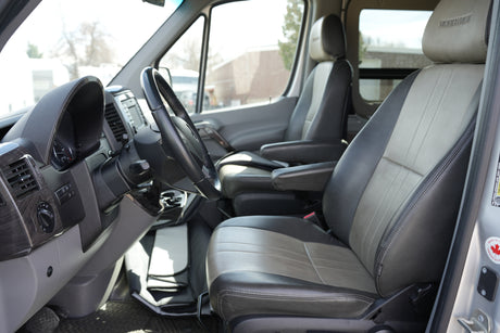 Spacious RV rental interior from the driver's perspective, showing two-tone leather seats, steering wheel, and dashboard.