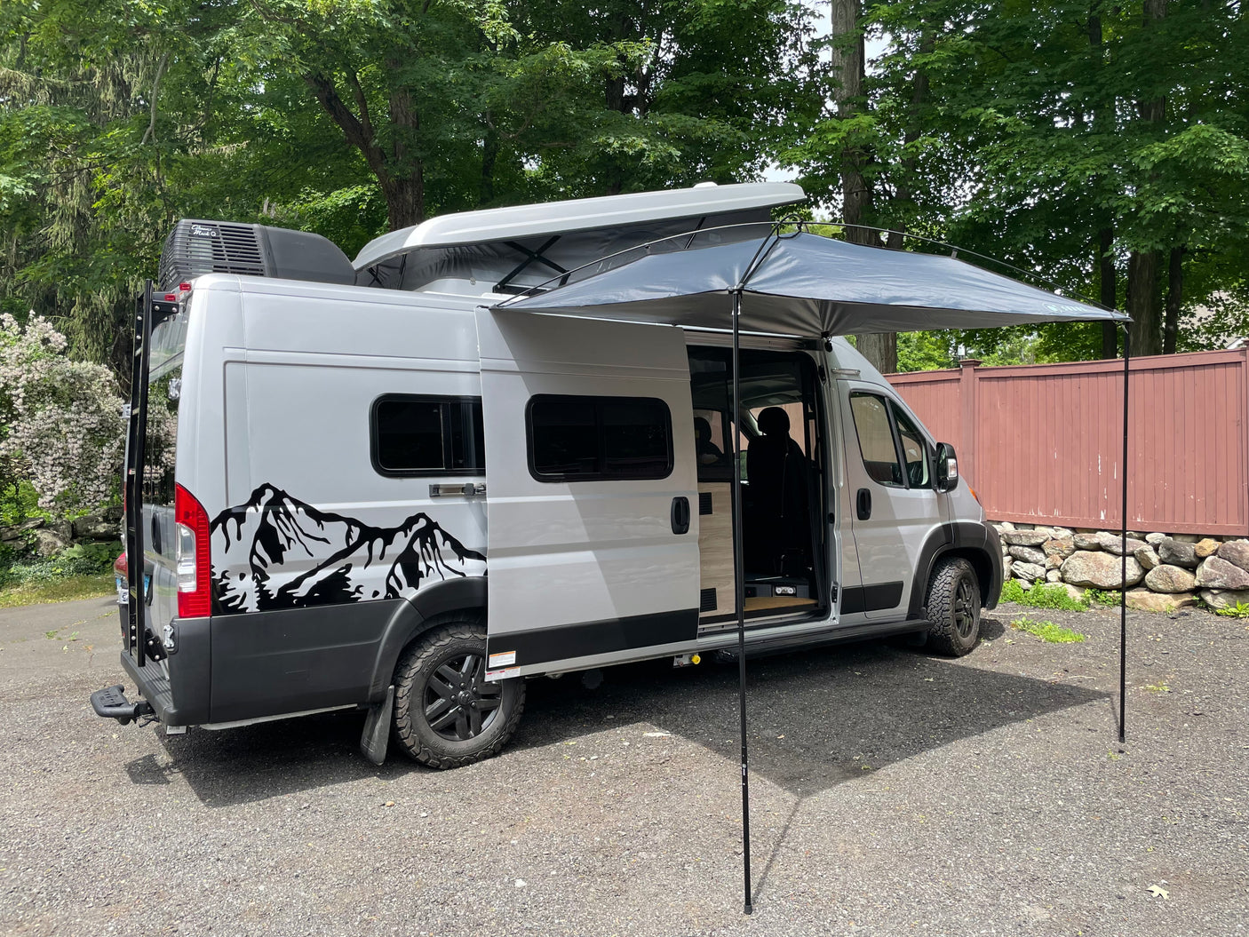 Silver rv rental campervan with pop-top open, extended awning, and side door open, ready for adventure or camping.