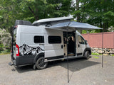 Silver rv rental campervan with pop-top open, extended awning, and side door open, ready for adventure or camping.