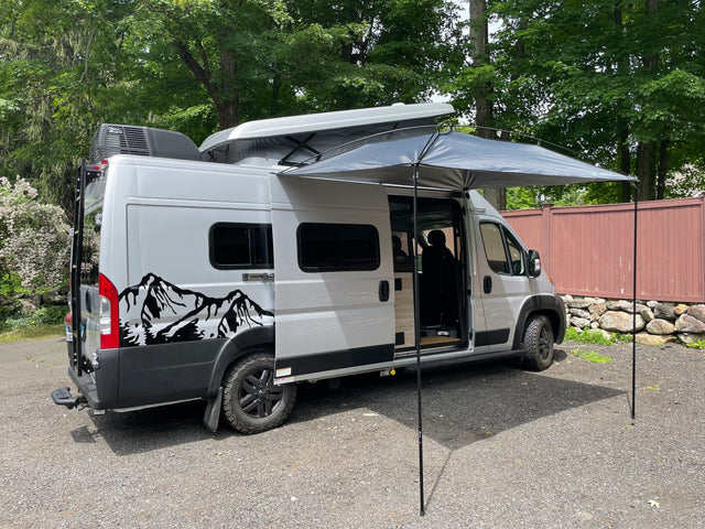 Silver rv rental campervan with pop-top open, extended awning, and side door open, ready for adventure or camping.