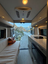 This rv rental offers a modern interior with kitchen, sofa, and a scenic view of desert mountains.