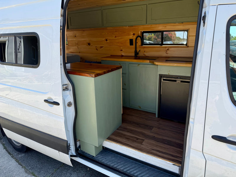 White camper van conversion interior: wood, green cabinets, sink, fridge. Great for RV rental! — photo 4
