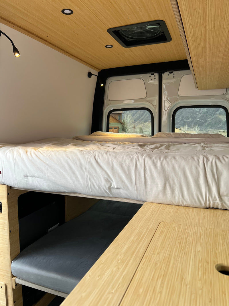 Cozy rv rental interior featuring an elevated bed, lower sleeping area, bamboo ceiling, and scenic mountain views out back. — photo 19