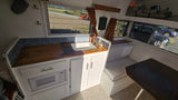 Cozy RV rental interior: kitchenette with wood counters, blue tiles, microwave. Dining nook & storage baskets.