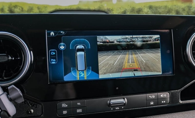 This RV rental's dashboard shows a rear camera view of a parking lot and active parking assist sensors on the infotainment screen. — photo 6