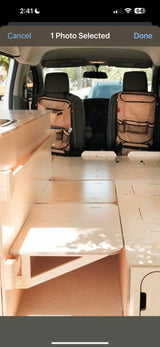 RV rental: Inside a camper van conversion, featuring light wood interior, modular bed, and seat back organizers.