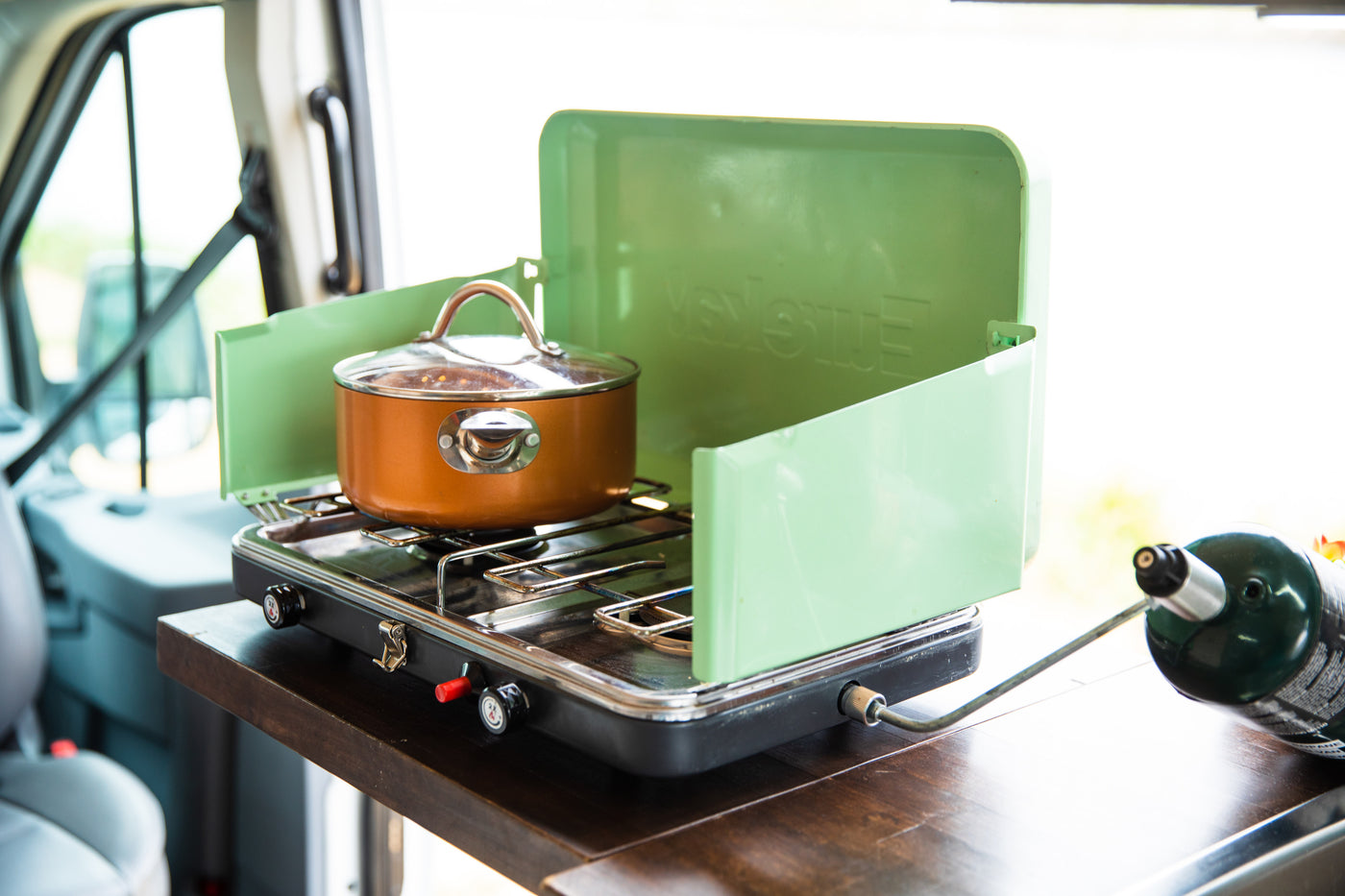 Cooking on a portable green Coleman propane stove with a copper pot, set up in an RV rental for easy camper van meals. — photo 14