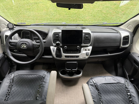 RV rental interior: clear view of the dashboard, Ram steering wheel, large infotainment screen, and detailed front seats.