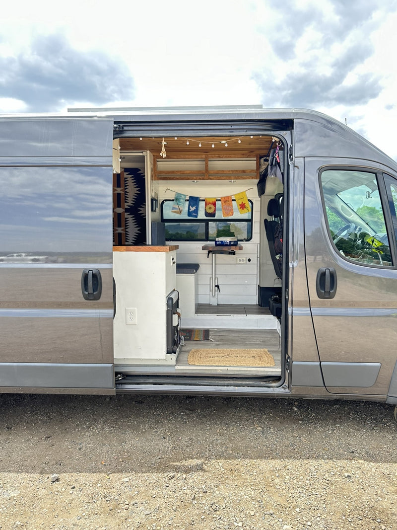 Custom camper van rv rental showcasing its cozy interior: kitchen, table, and bed visible through the open side door. Perfect for van life. — photo 4