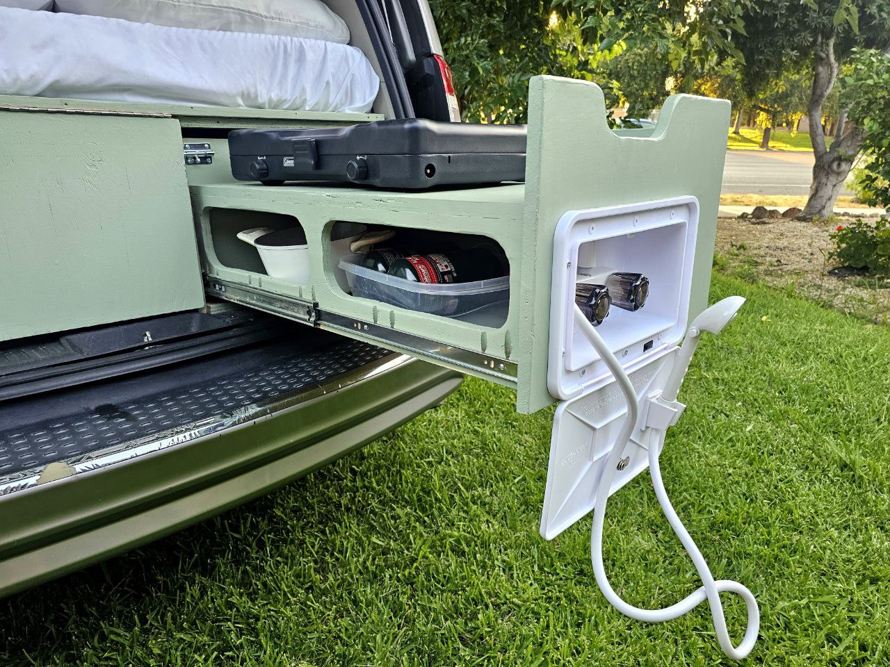 RV rental: View of a camper van's pull-out kitchen with stove and an integrated outdoor shower for camping convenience. — photo 20