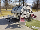 Compact teardrop trailer, ideal for rv rental, parked with camping chairs & grass mat. Ready for your next road adventure!