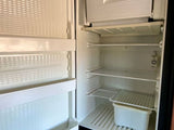 Clean, empty RV rental fridge interior. Wire shelves, door storage, and bottom bin await your groceries.