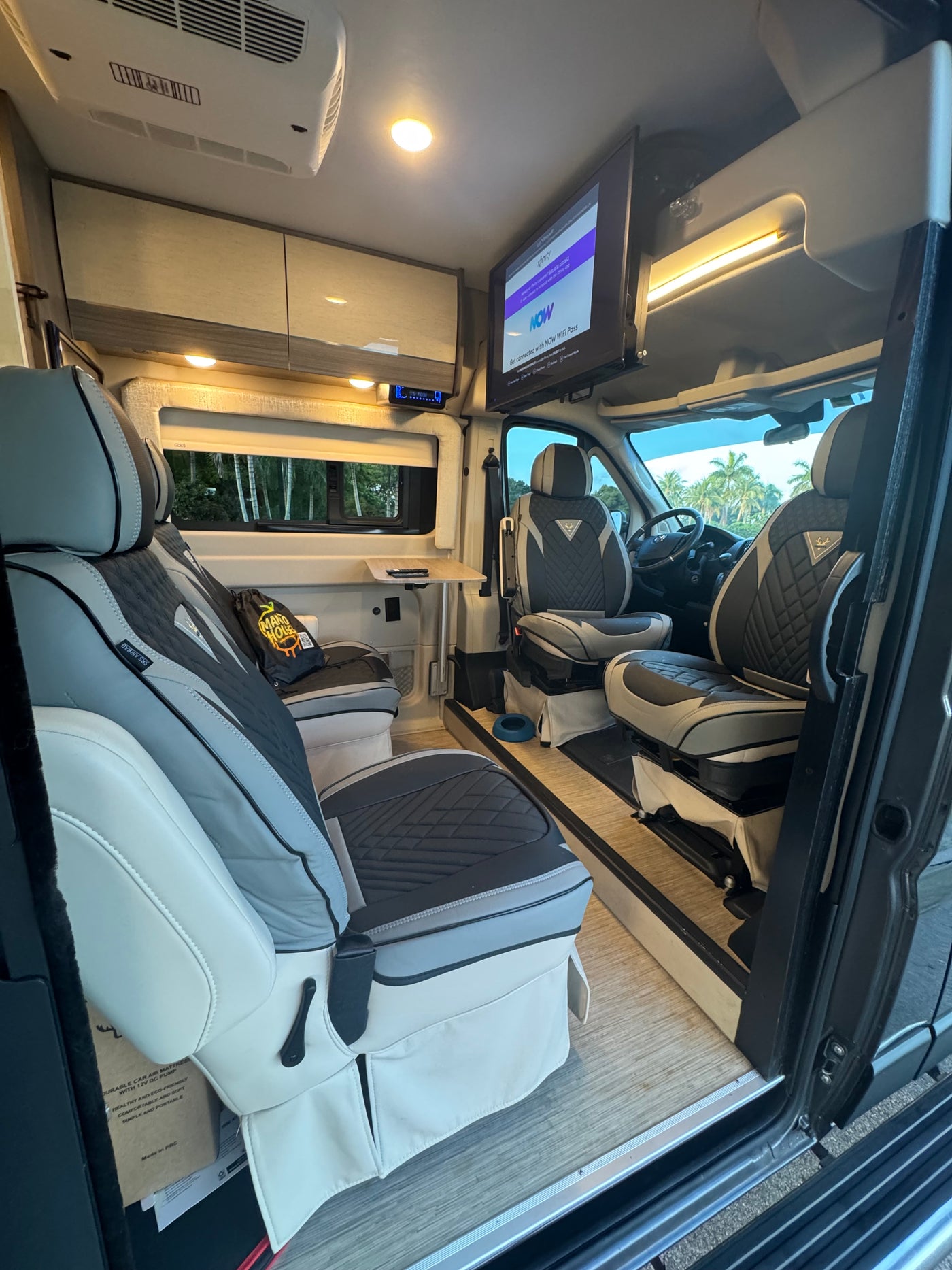This comfy camper van rv rental interior offers swivel seating, TV, and climate control, ideal for mobile living. — photo 15
