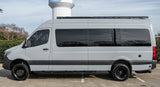 Light grey adventure camper van for rv rental, featuring dark tinted windows and a roof rack. Perfect for your next journey.