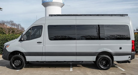Light grey adventure camper van for rv rental, featuring dark tinted windows and a roof rack. Perfect for your next journey.