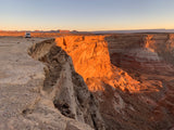 RV rental enjoys a stunning sunset view over vast desert cliffs and canyons, a white van parked near the edge.