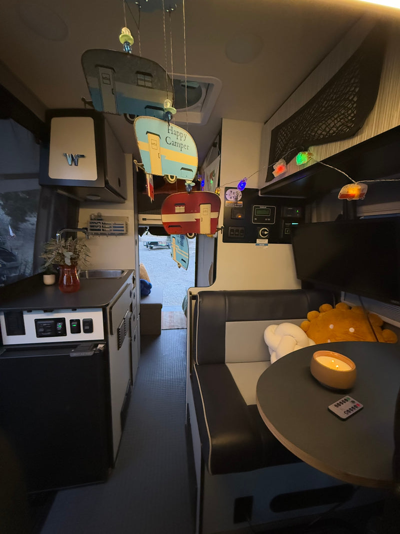 Cozy RV rental interior showing a kitchenette, dining booth, and decorative camper elements. — photo 11
