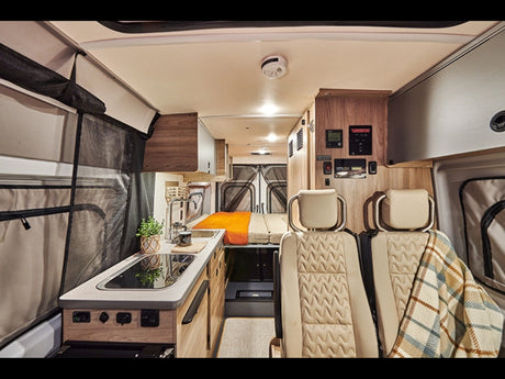 Spacious RV rental interior featuring a modern kitchen, comfortable bed, and front seating for ideal travel.
