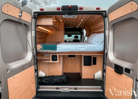 RV rental: rear view of wood-paneled interior, bed, storage, and outdoor shower hookup, ready for adventure.