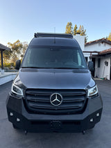A dark gray Mercedes-Benz Sprinter van with custom bumper, off-road lights, and roof light bar, ready for your RV rental.