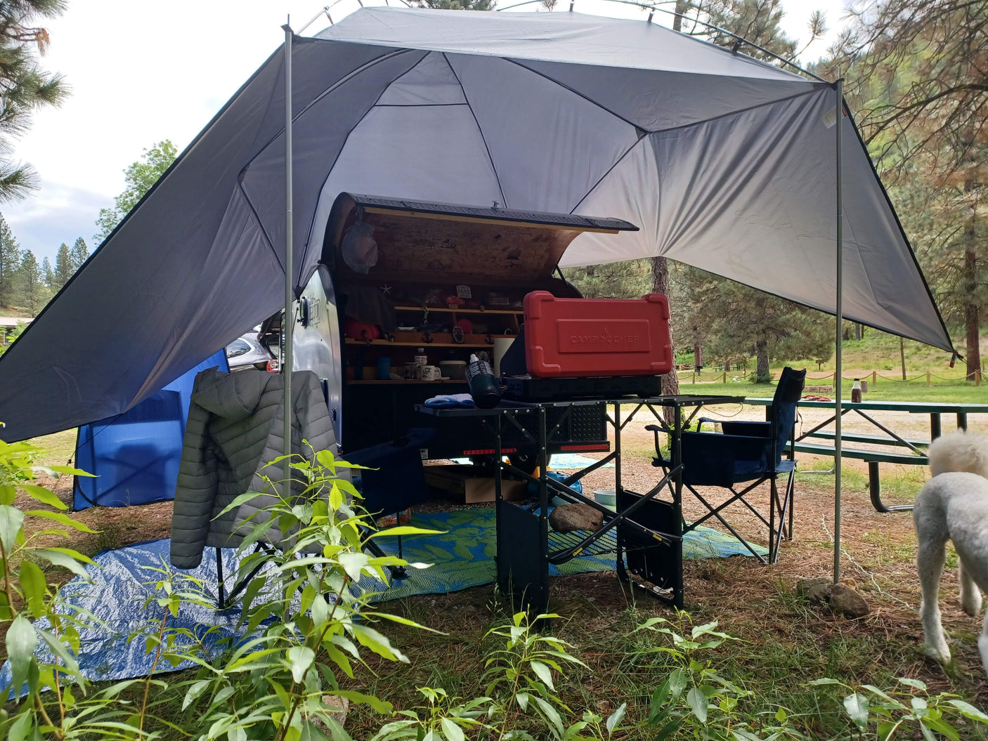 Spacious awning and outdoor kitchen setup with a Camp Chef grill, extending from a compact RV rental for comfortable camping.