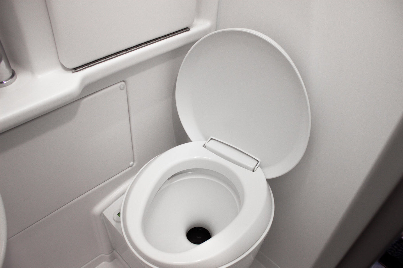 A clean, white toilet with its lid up, seen inside the compact bathroom of an RV rental.