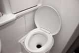 A clean, white toilet with its lid up, seen inside the compact bathroom of an RV rental.