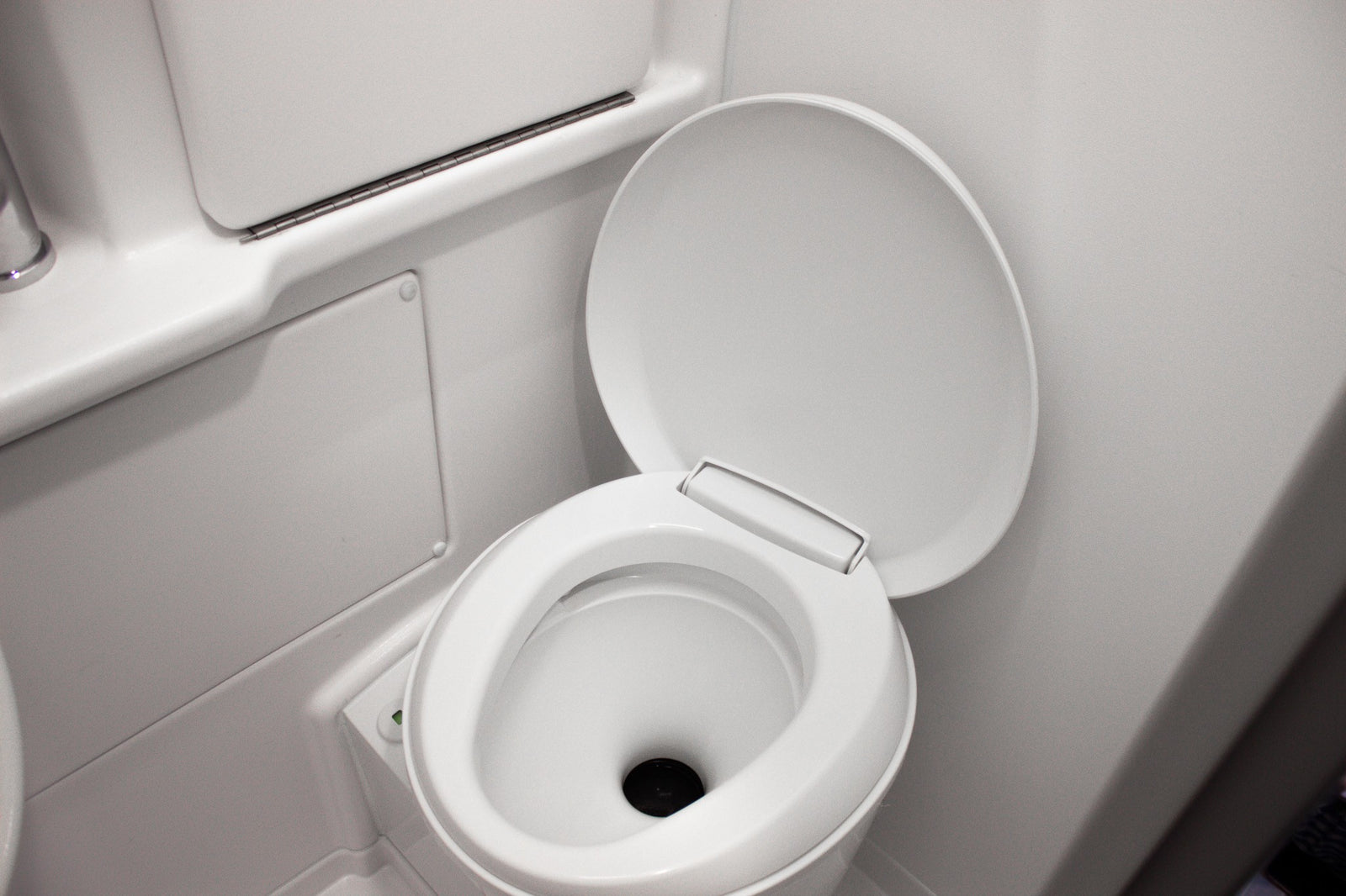 A clean, white toilet with its lid up, seen inside the compact bathroom of an RV rental.
