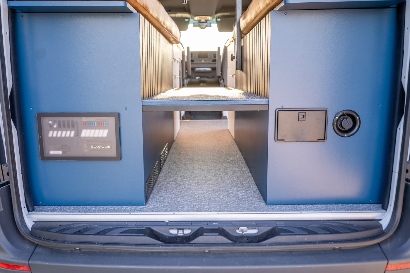 Spacious rv rental interior from the rear, showing custom blue storage, an Ecoflow panel, and a raised bed platform. — photo 11