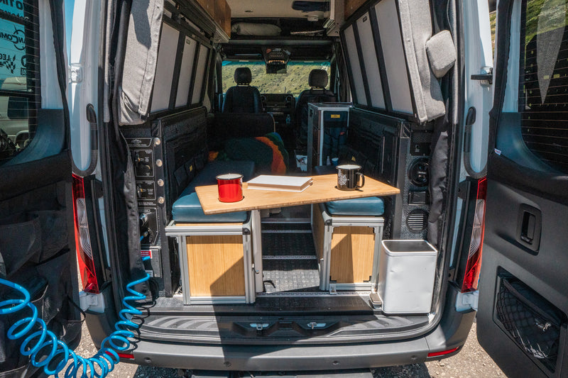 Back of an RV rental showing its practical interior with a bed, table, and storage for comfortable mobile living. — photo 12