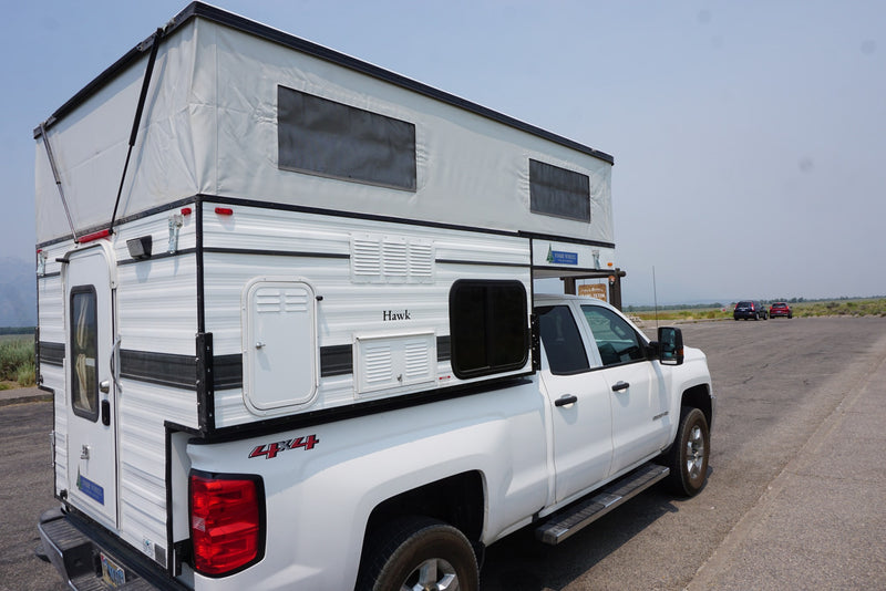 White 4x4 pickup with a pop-top Four Wheel Campers Hawk truck camper, perfect for an RV rental. — photo 3