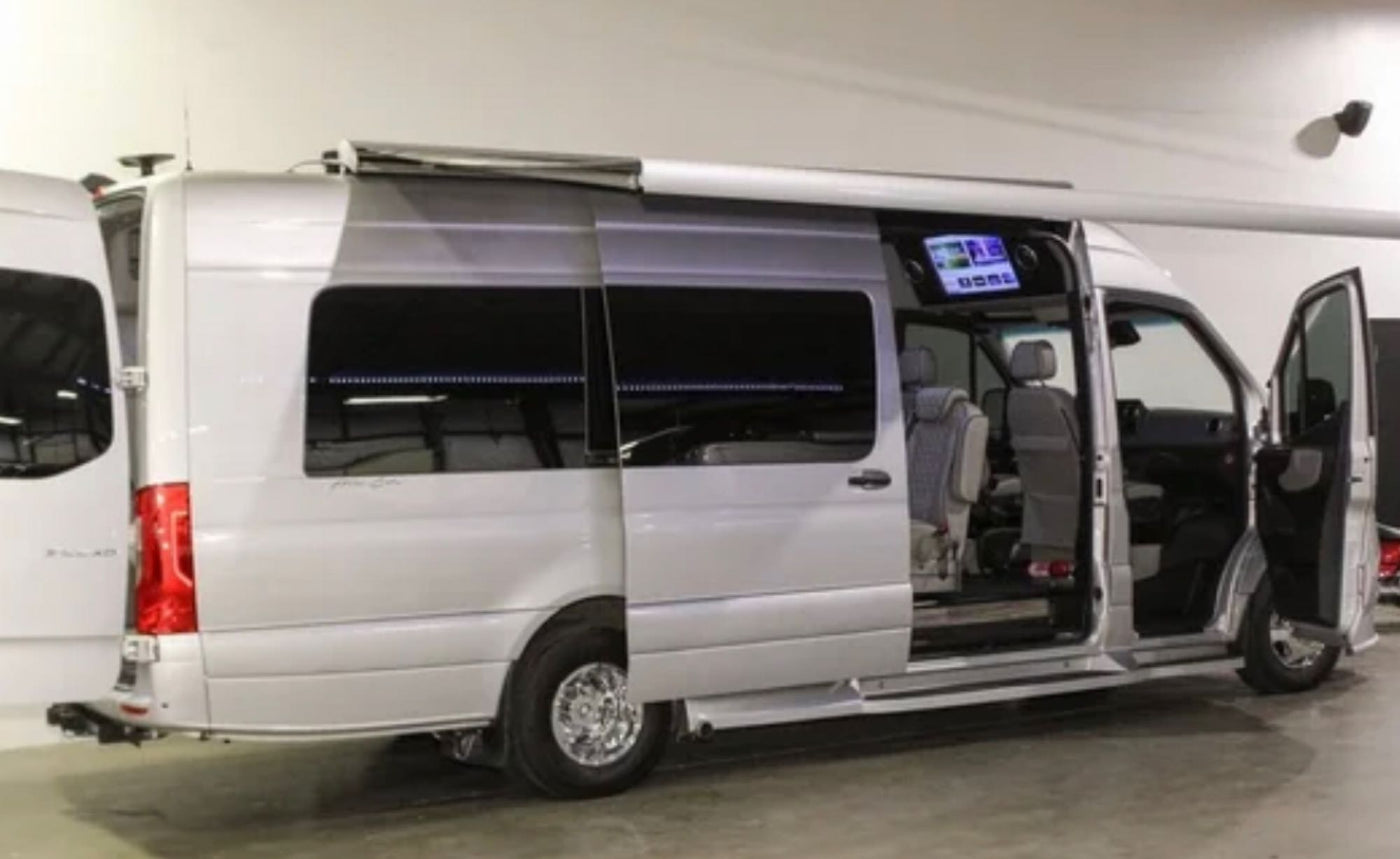 This silver luxury RV camper van, with doors open revealing its plush interior and extended awning, is ideal for rv rental adventures. — photo 4