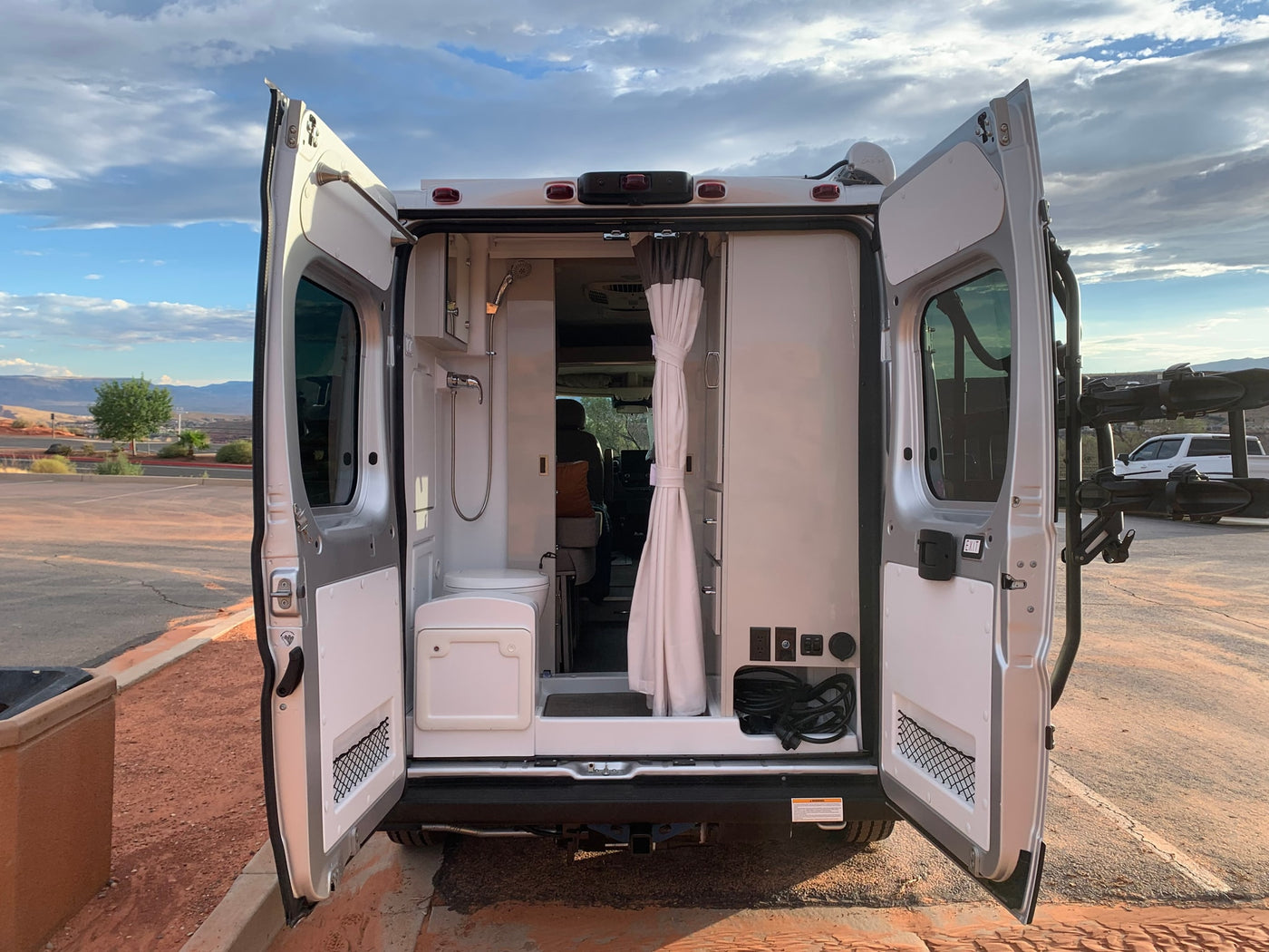 Rear view inside an RV rental shows a compact bathroom (toilet, shower) and power outlets. Ready for your next adventure. — photo 2
