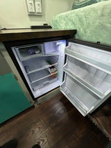 Explore this RV rental's interior, featuring an open, well-lit mini-fridge with drinks, shelving, and a small freezer for your journey.