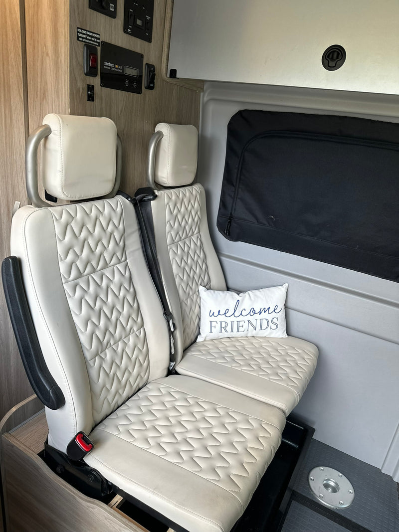 Cozy RV rental interior with inviting patterned seating, welcome pillow, solar controls, and holding tank heater switch. — photo 11