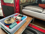 Gear-packed RV rental: organized kitchen supplies on pull-out counter, comfy bed in back.