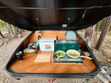 RV rental: Inside a camper's outdoor kitchen, cooking broccoli and burgers on a propane stove by the lake.