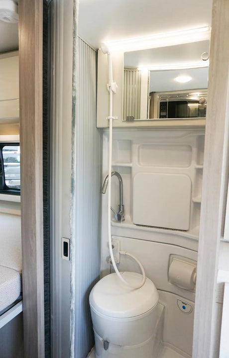 Inside an RV rental: a compact wet bath with a toilet, shower, and sink, designed for efficient mobile living.