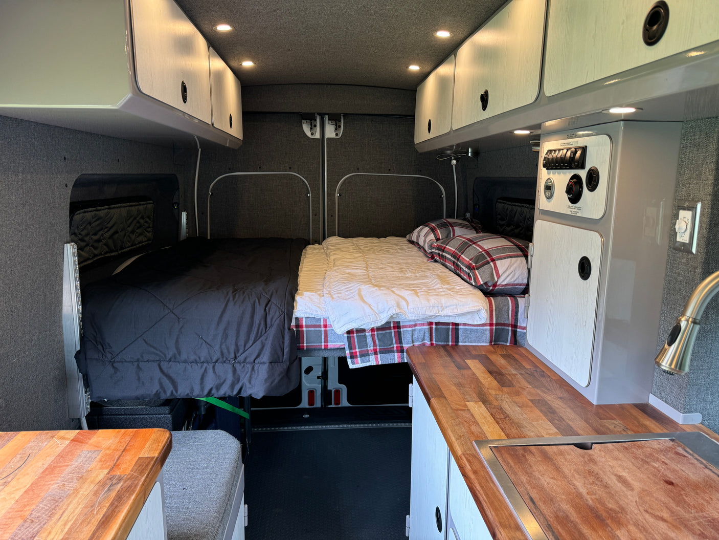 Spacious RV rental interior featuring twin sleeping areas, overhead storage, and a functional kitchen counter.