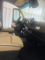 RV rental interior: Cream quilted seats, modern black dashboard, and steering wheel of a spacious van.