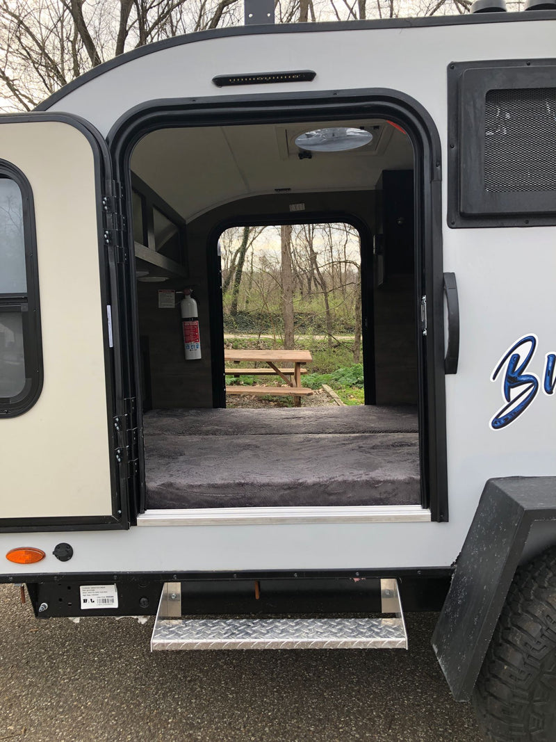 Step inside this cozy RV rental's inviting interior, showcasing a comfy bed, fire extinguisher, and campsite view. — photo 7