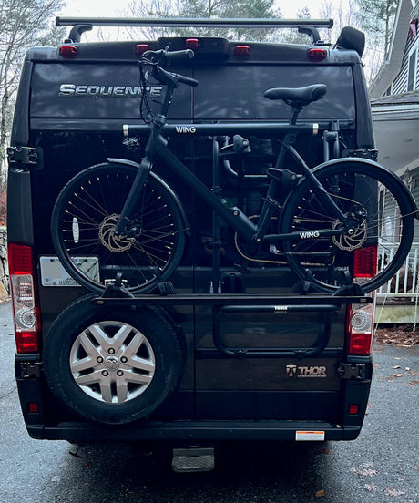 Rear of black Thor Sequence RV rental with two Wing e-bikes on a rear bike rack, ready for outdoor adventures.
