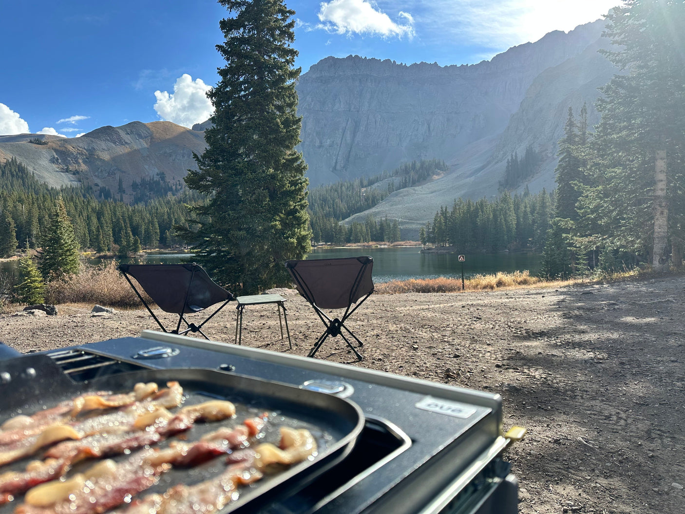 Enjoying a delicious bacon breakfast by the lake with stunning mountain views, perfect for an RV rental outdoor adventure.