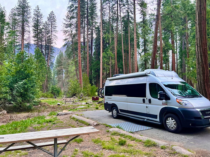 Experience outdoor travel! This RV rental campervan is parked at a scenic campsite surrounded by tall trees and mountains. — photo 4