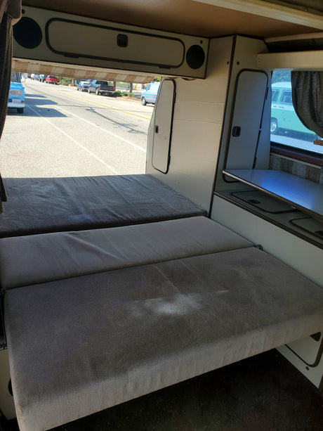 RV rental: Camper van interior features convertible beds & storage, offering a clear road view.