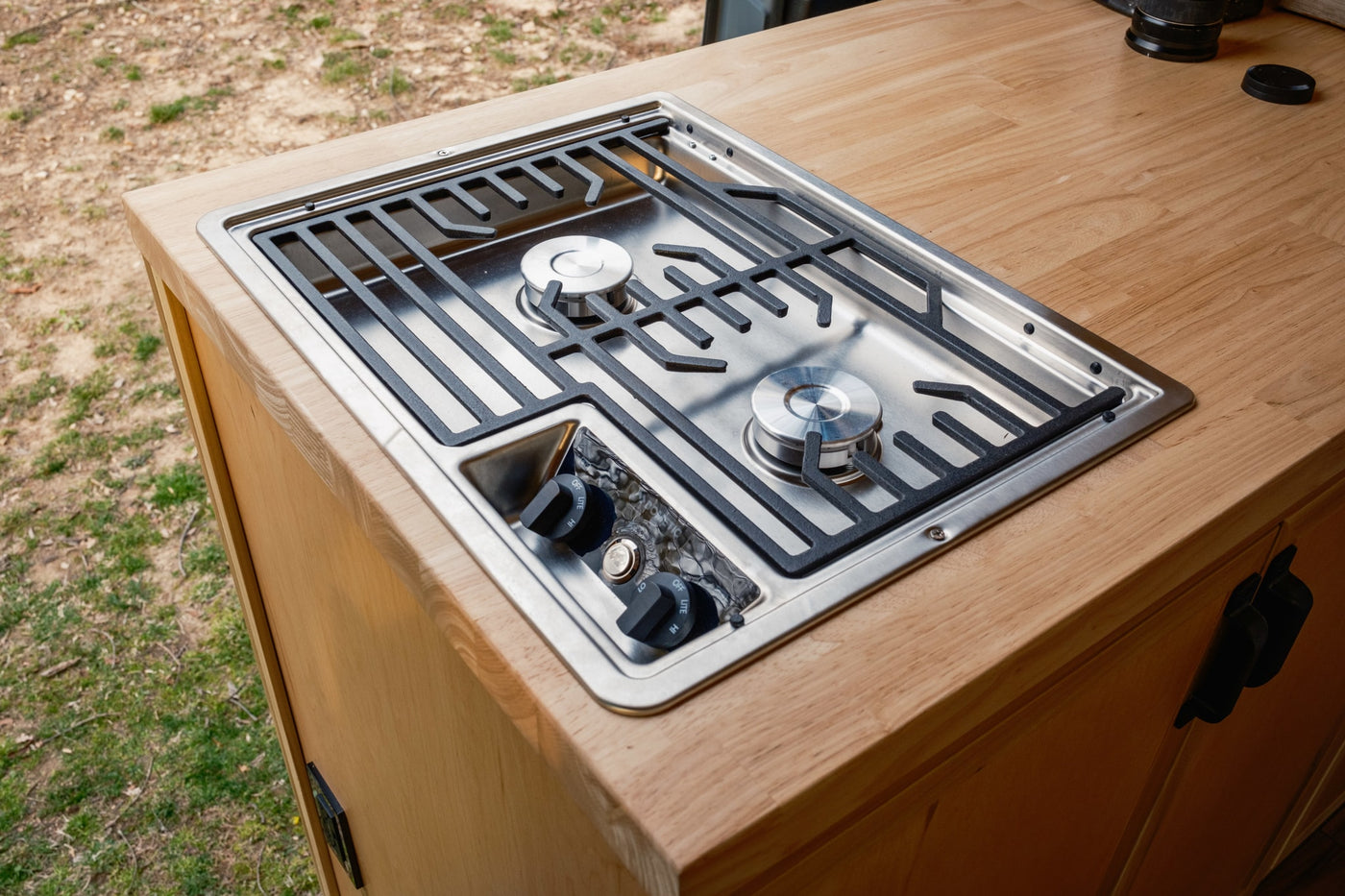 This rv rental features a sleek, built-in two-burner gas cooktop with control knobs, integrated into a light wood countertop. — photo 16