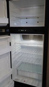 Clean, empty refrigerator and freezer interior, ideal for an RV rental. Features wire shelves and a crisper drawer.