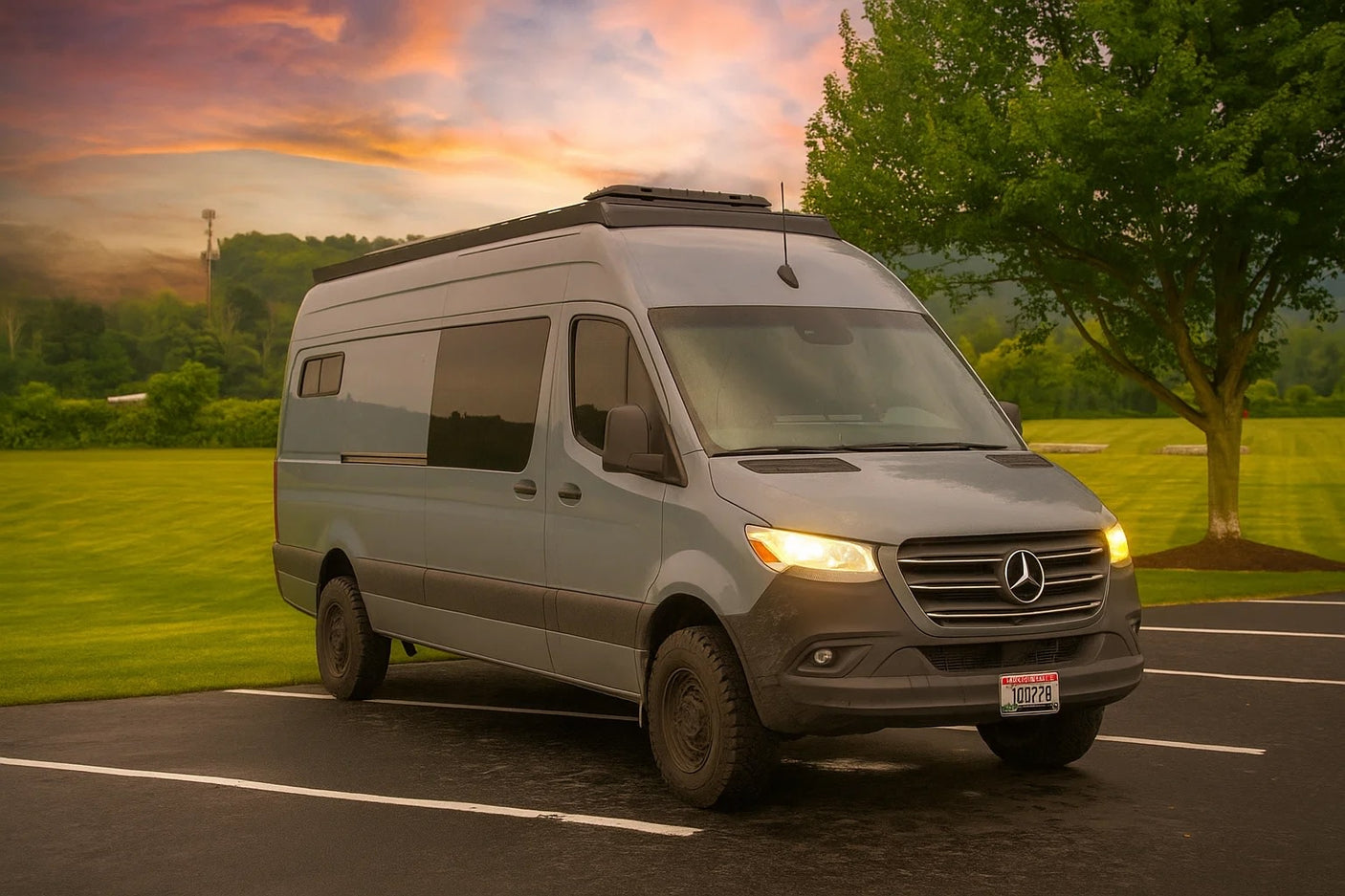 Grey Mercedes-Benz Sprinter camper van available for RV rental, parked with lights on, under a dramatic sky.