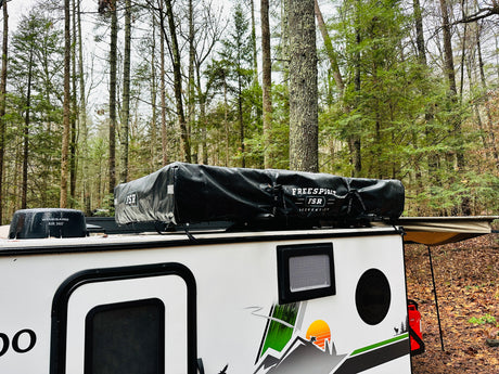 RV rental camper featuring a Freespirit rooftop tent and Winegard antenna, perfect for forest camping adventures.